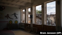 Biblioteca distrusă a unei școli este văzută prin ferestrele sparte ale unei săli de sport din Kupiansk, Ucraina, 23 august 2023.