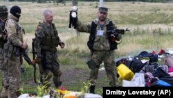 Бойовик російських гібридних сил тримає іграшку, виявлену на місці падіння уламків «Боїнга», збитого російською установкою «Бук», в результаті чого загинуло 298 людей, в тому числі 80 дітей. Донеччина, неподалік села Грабове, 19 липня 2014 року 